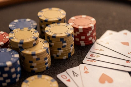 Goldene Poker-Chips und Spielkarten auf dunklem Tisch im Vox Casino