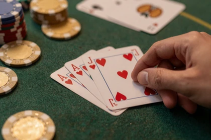 Poker-Hand mit Royal Flush auf dunklem Spieltisch mit goldenen Chips bei Vox Casino
